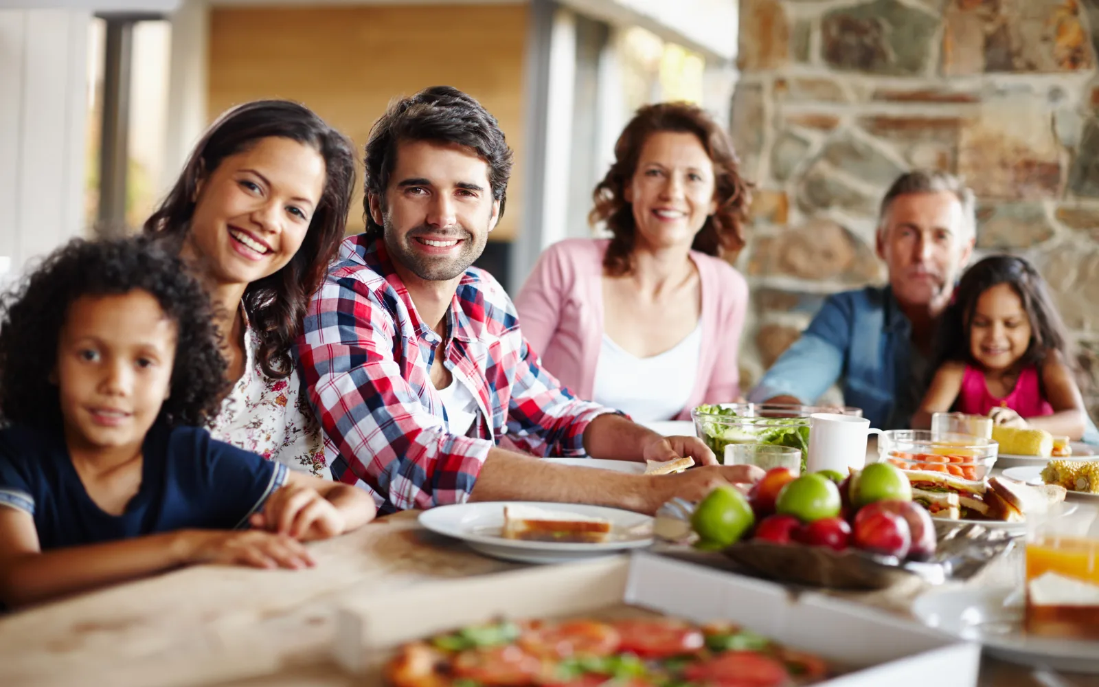 Multigenerational family sharing a relaxed pizza lunch together at home.